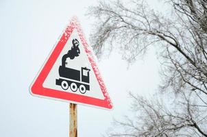 Railway crossing without barrier. A road sign depicting an old black locomotive, located in a red triangle photo