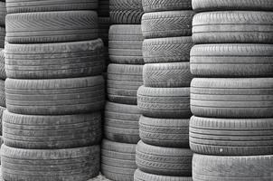 Old used tires stacked with high piles in secondary car parts shop garage photo