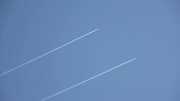 Two military jets and an airliner flying high in the sky leaving contrails in the clear blue sky. video