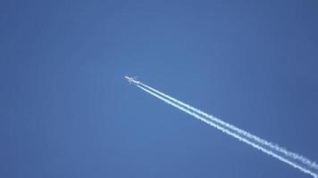 straalvliegtuig dat hoog in de lucht vliegt, laat contrails achter in de heldere blauwe lucht. video