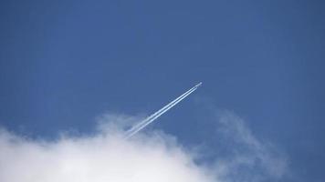 Jet airliner flying out of clouds in the sky leaves contrails video