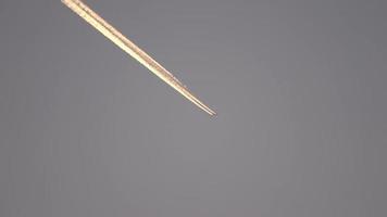 avião a jato voando alto no céu deixa rastros no pôr do sol. video