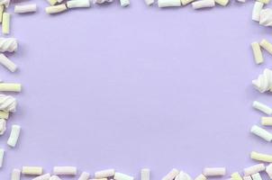 Colorful marshmallow laid out on violet paper background. pastel creative textured framework. minimal photo