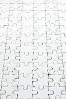 Close up of a white jigsaw puzzle in assembled state in perspective. Many components of a large whole mosaic are united photo