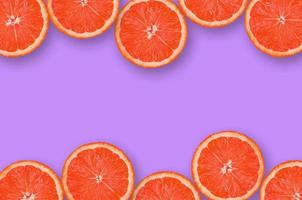 Frame of grapefruit citrus slices on bright purple background photo