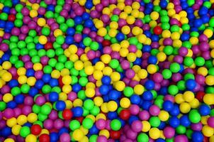 muchas bolas de plástico de colores en una piscina para niños en un parque infantil. patrón de primer plano foto