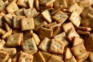 Background texture of small edible squares baked from dough and sprinkled with salt. A lot of salt cracker photo