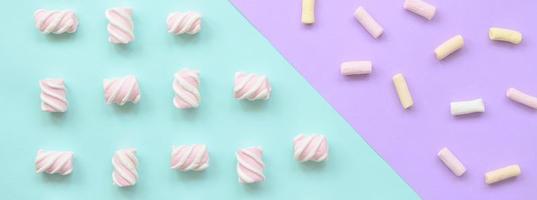 Colorful marshmallow laid out on violet and blue paper background. pastel creative textured pattern. minimal photo