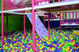 muchas bolas de plástico de colores en una piscina para niños en un patio de recreo foto