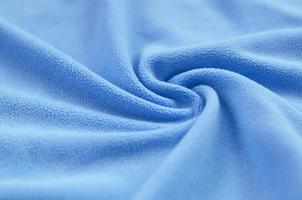 The blanket of furry blue fleece fabric. A background of light blue soft plush fleece material with a lot of relief folds photo