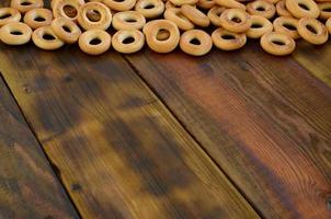 A lot of fresh yellow bagels lie on the surface of the old dark wood. A popular kind of flour products. One of the traditional Russian treats for tea photo