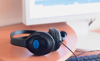 Big black headphones lie on the wooden desktop of the sound designer photo