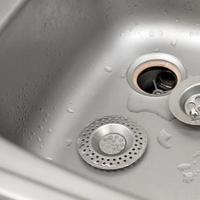 Silvery kitchen sink with a disassembled protective filter during the repair process photo