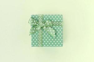 Small green gift box with ribbon lies on a lime background photo