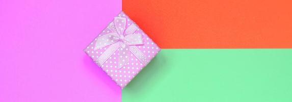 Small pink gift box lie on texture background of fashion pastel turquoise, red and pink colors paper photo