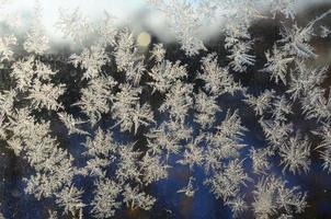 Snowflakes frost rime macro on window glass pane photo