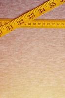 Yellow measuring tape lies on a gray knitted fabric photo