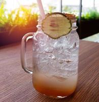 glass of ice lemonade on wooden table photo