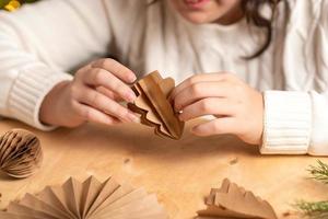 girl makes Christmas tree decorations out of paper with her own hands. step 5. step-by-step instruction photo