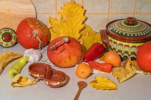 Seasonal harvest of pumpkins and vegetables, ingredients for preparing a dish, advertising and autumn concept - close-up of pumpkins and leaves on the table at home photo