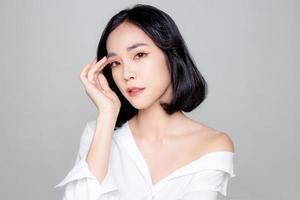 Asian woman short hair with Perfect clean fresh skin. Cute female model with natural makeup and sparkling eyes on white isolated background. Facial treatment, Cosmetology, beauty Concept. photo