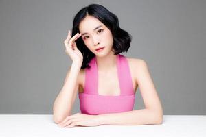 Asian woman short hair with Perfect clean fresh skin. Cute female model with natural makeup and sparkling eyes on grey isolated background. Facial treatment, Cosmetology, beauty Concept. photo