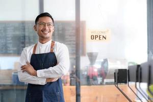 inicio exitoso pequeño empresario propietario sme stand con tablet smartphone en cafetería restaurante. retrato del propietario de un café barista de un hombre bronceado asiático. pyme empresario vendedor concepto de negocio foto