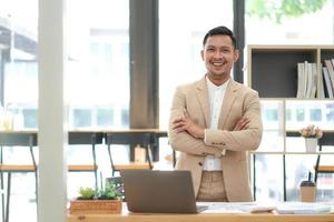 Asian businessman standing by his desk in office photo