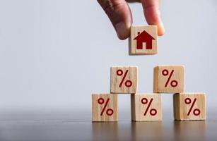 Hand building a house by wooden cubes with the percentage sign on them. Concept of Interest rate financial mortgage rates, home loans, home refinance, wooden block with percentage symbol and up arrow. photo