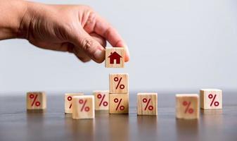 Hand building a house by wooden cubes with the percentage sign on them. Concept of Interest rate financial mortgage rates, home loans, home refinance, wooden block with percentage symbol and up arrow. photo