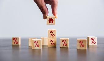 Hand building a house by wooden cubes with the percentage sign on them. Concept of Interest rate financial mortgage rates, home loans, home refinance, wooden block with percentage symbol and up arrow. photo