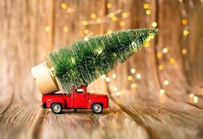 coche en miniatura sobre fondo de madera con luz de navidad, regalo de vacaciones. foto