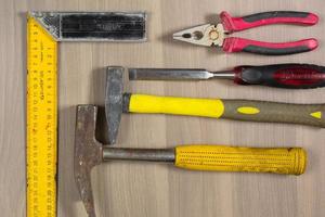 Different tools on a wooden background. Hammer, chisel, pliers, square photo