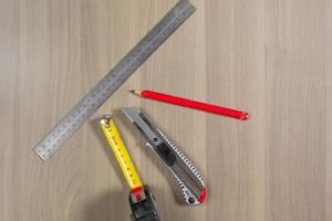 Diferentes herramientas en un fondo de madera. regla, lápiz, cuchillo, ruleta foto