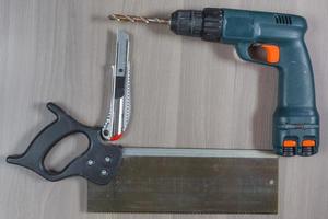 Diferentes herramientas en un fondo de madera. taladro, cuchillo, sierra foto