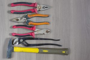 Diferentes herramientas en un fondo de madera. alicates, alicates, alicates, martillo foto