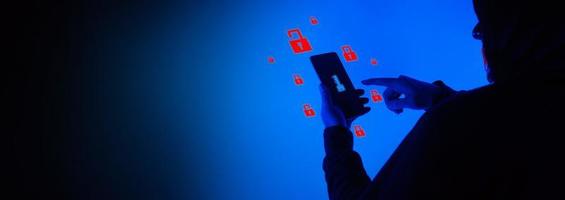 Digital security Concept. Anonymous hacker with mask holding smartphone hacked. photo