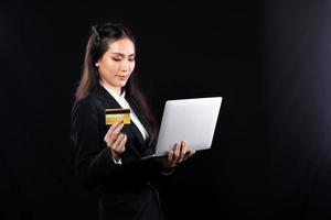 Business woman hold gold credit card and shopping online with internet financial banking payment when purchasing. Technology help person shopping at home in e-commerce store on mobile phone or laptop photo
