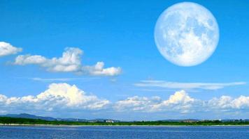 super lune bleue remonte le ciel bleu et les nuages sur le lac et la colline de montagne backgroundtime lapse video