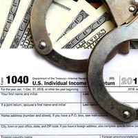 Police handcuffs lie on the tax form 1040. The concept of problems with the law in the aftermath of non-payment of taxes photo