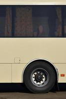 Photo of the hull of a large and long yellow bus with free space for advertising. Close-up side view of a passenger vehicle for transportation and tourism