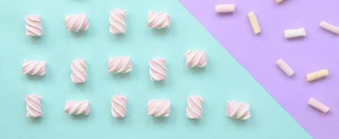 Colorful marshmallow laid out on violet and blue paper background. pastel creative textured pattern. minimal photo