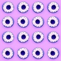 Many small plastic donuts lies on a pastel colorful background. Flat lay minimal pattern. Top view photo