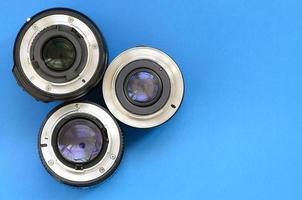 Several photographic lenses lie on a bright blue background. Space for text photo