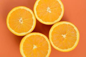 Top view of a several orange fruit slices on bright background in orange color. A saturated citrus texture image photo