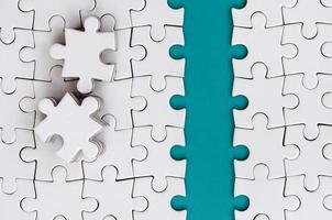 The blue path is laid on the platform of a white folded jigsaw puzzle. The missing elements of the puzzle are stacked nearby. Texture image with space for text photo