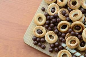 túbulos crujientes, bolas de chocolate y bagels yacen sobre una superficie de madera. mezcla de varios dulces foto