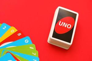 TERNOPIL, UKRAINE - MAY 15, 2022 Many colorful UNO game cards on red background. UNO is an American shedding-type card game that is played with a specially printed deck photo