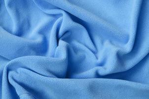 The blanket of furry blue fleece fabric. A background of light blue soft plush fleece material with a lot of relief folds photo
