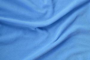 The blanket of furry blue fleece fabric. A background of light blue soft plush fleece material with a lot of relief folds photo